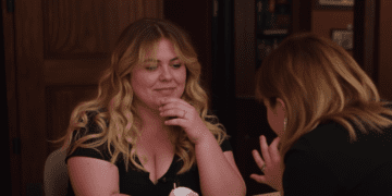 Author Colleen Hoover smiles while signing a book for a fan at an event.