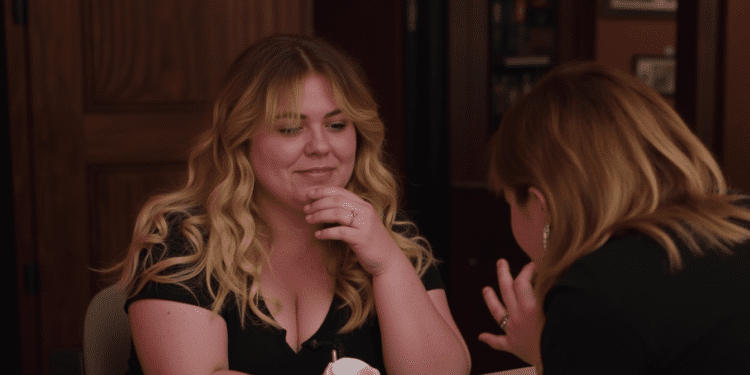 Author Colleen Hoover smiles while signing a book for a fan at an event.